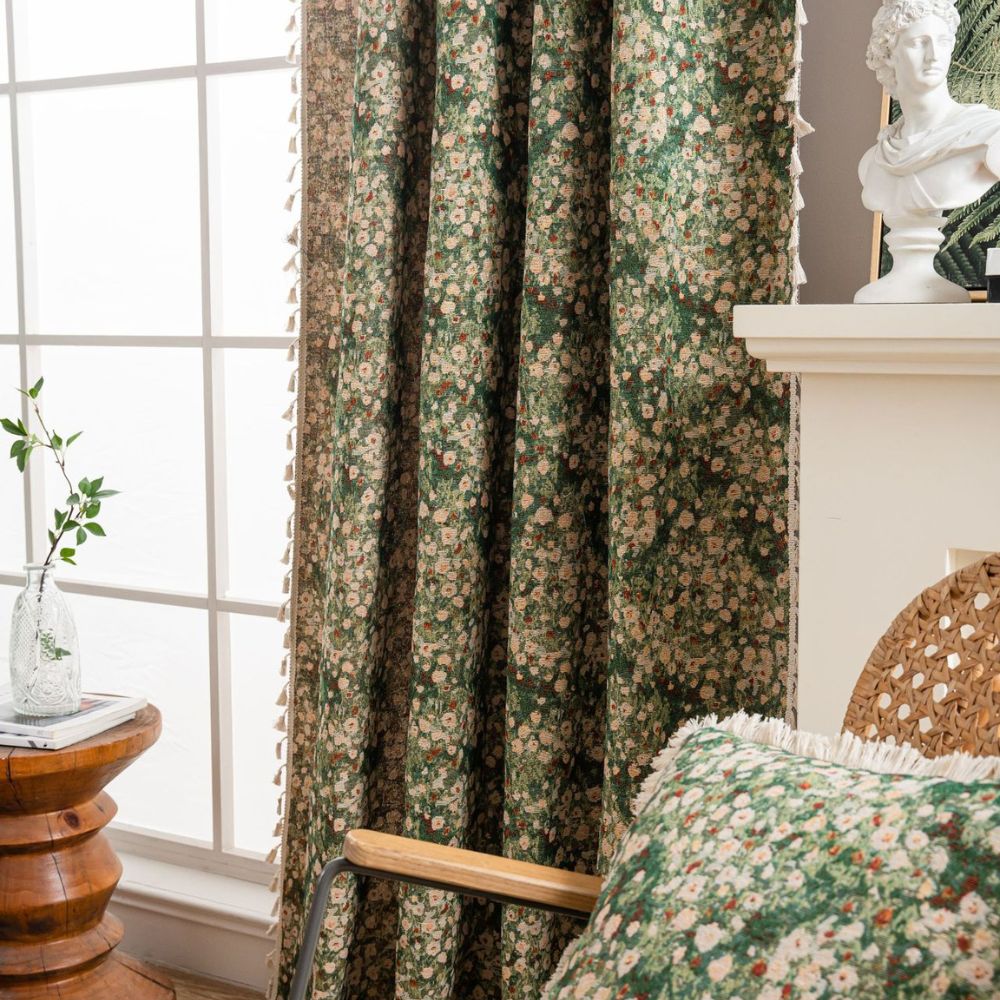 Green floral tapestry curtain with tassels, next to a window and a chair with a matching pillow.