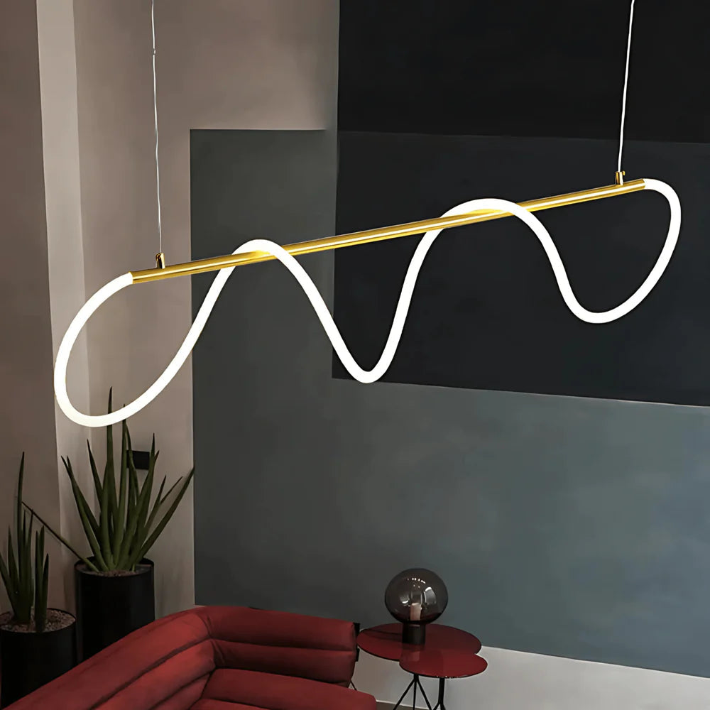 Modern black chandelier with a wavy silicone LED rope and brass accents, hanging over a red sofa.