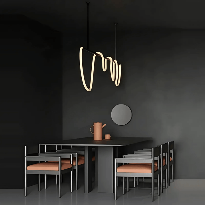 Black modern chandelier with a wavy silicone LED rope hanging above a dark dining table with chairs.