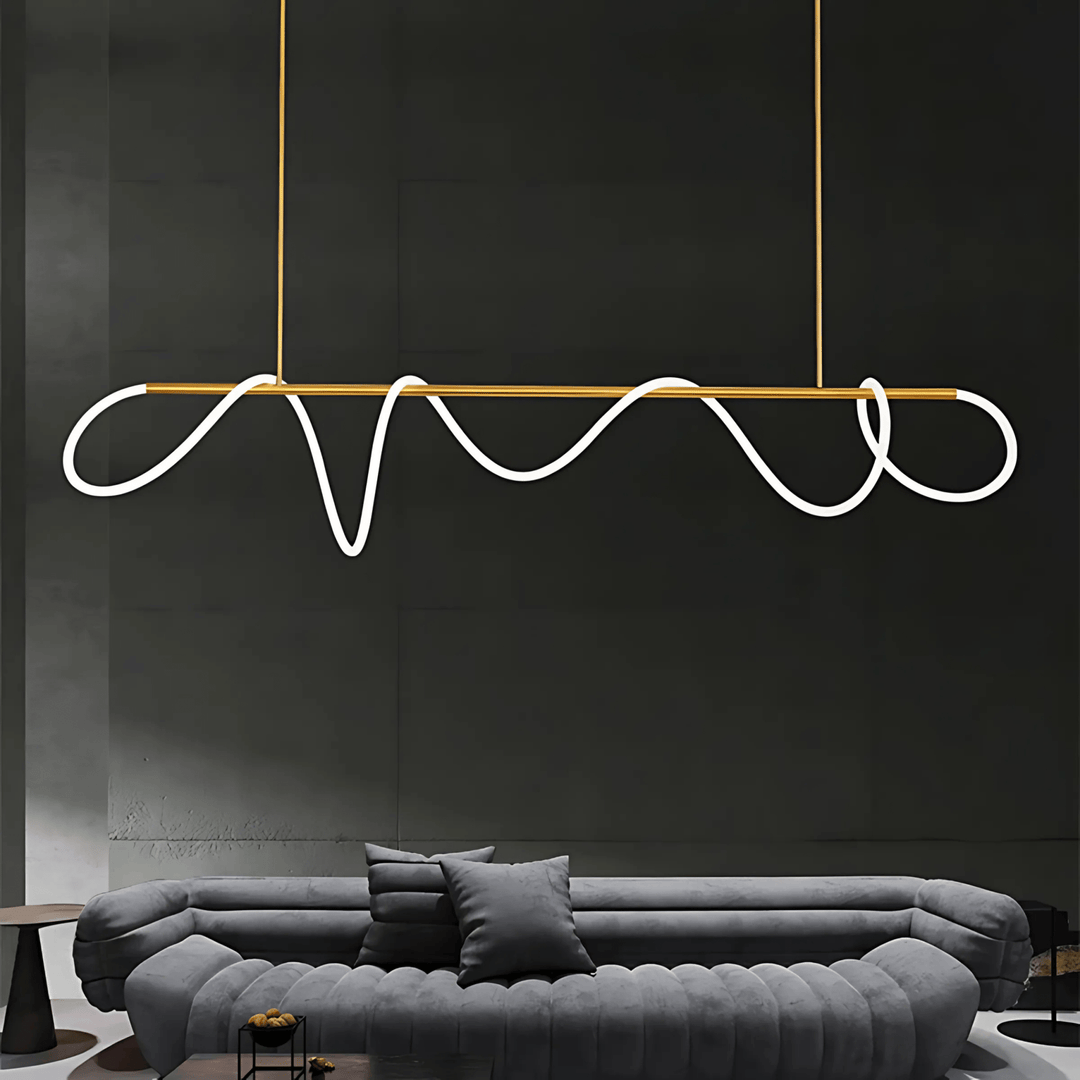 Modern black chandelier with a wavy silicone LED rope and gold accents, suspended above a grey sofa.