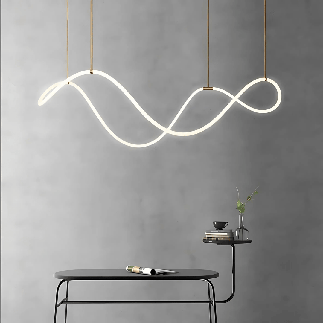 Modern black chandelier with a flowing, wavy design, suspended by thin cords against a gray wall.