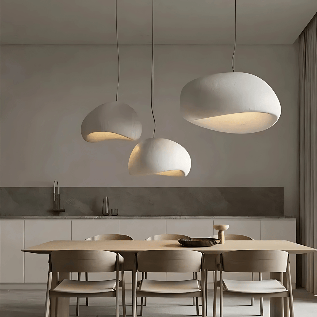Three off-white Wabi-Sabi pendant lights hanging over a wooden dining table.