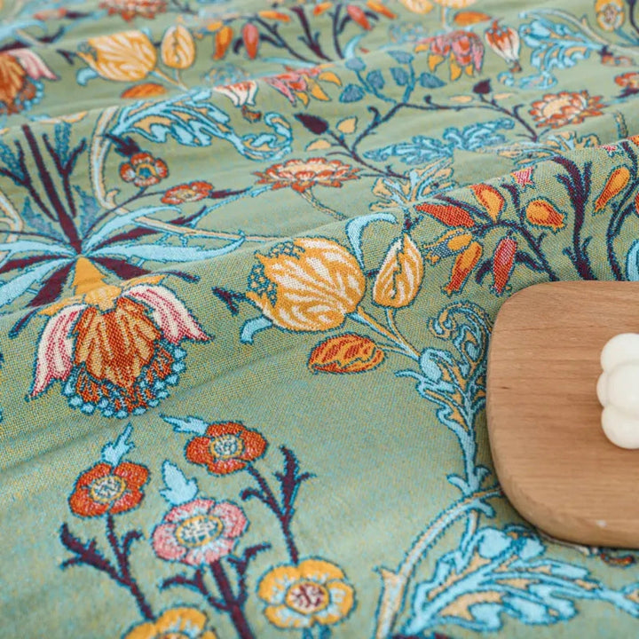 Greenery floral cotton blanket with tassel trim and a wooden coaster with a white candle.