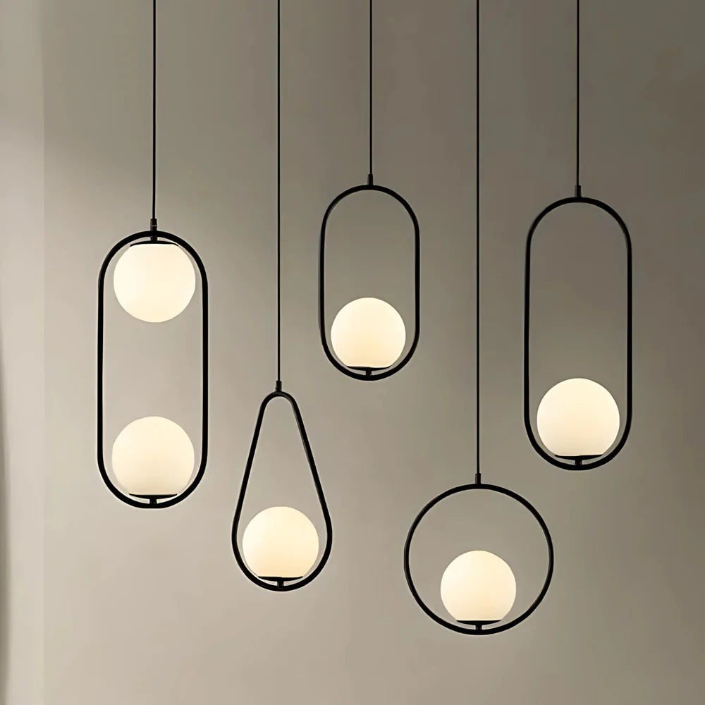Five minimalist pendant lights with black metal frames and frosted glass globes against a gray wall.