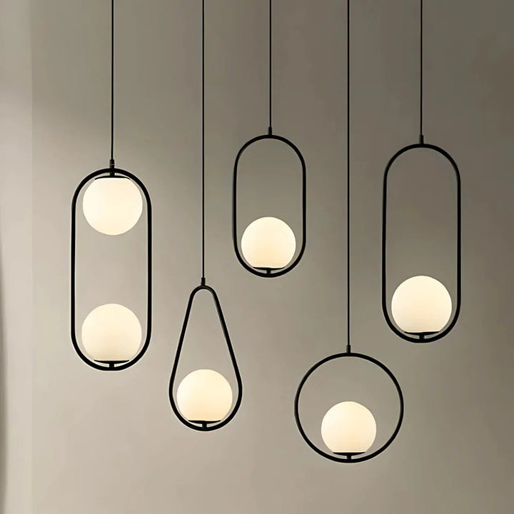 Five minimalist pendant lights with black metal frames and frosted glass globes against a gray wall.