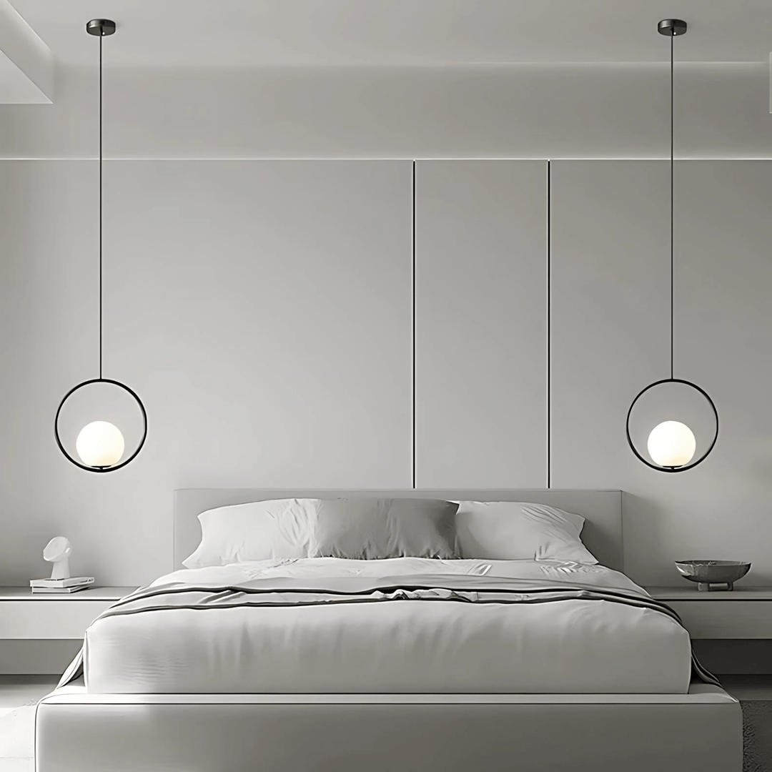 Minimalist black ring pendant light with a frosted glass globe hanging over a bed.