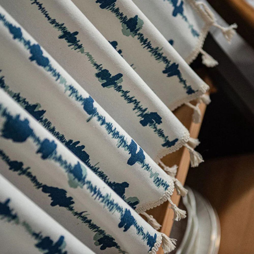 White cabinet curtain with blue inkblot pattern and tassel fringe.