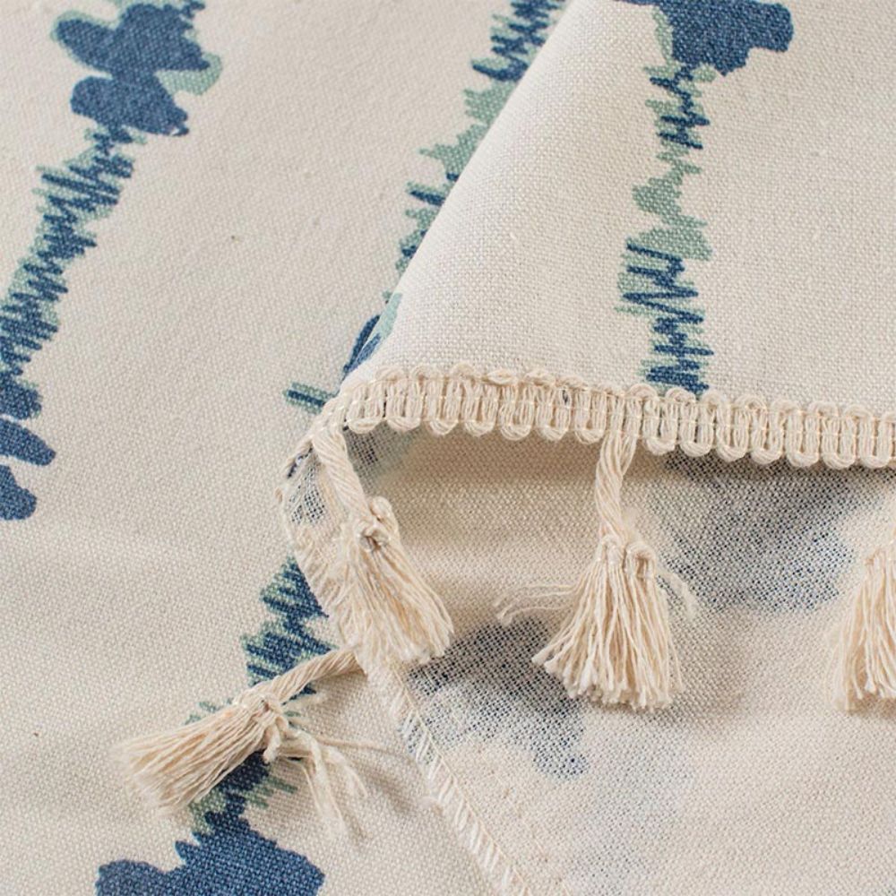 Close-up of a cabinet curtain with a blue inkblot pattern and a decorative tassel fringe.