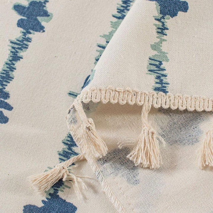 Close-up of a cabinet curtain with a blue inkblot pattern and a decorative tassel fringe.