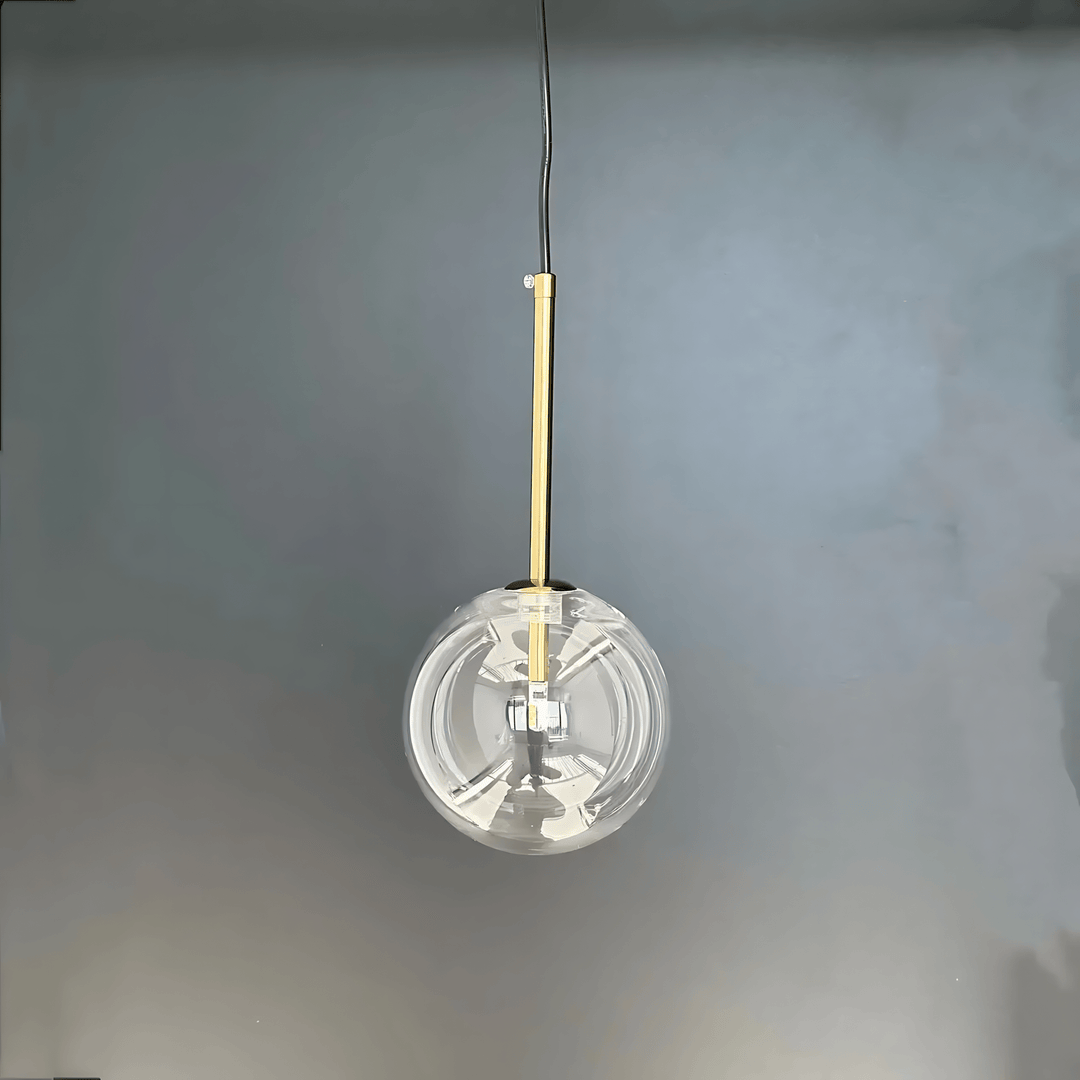 Modern glass pendant light with a gold stem against a gray background.