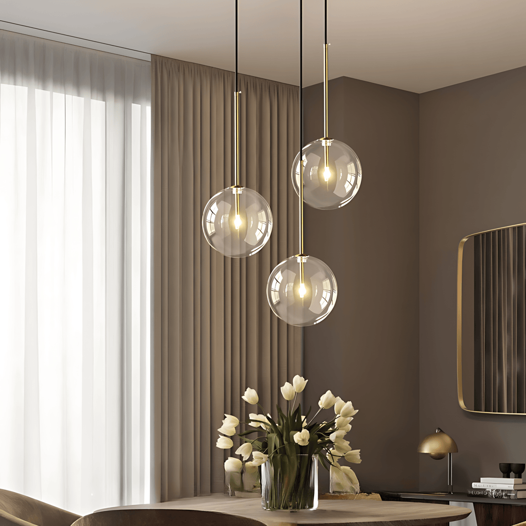 Three clear glass globe pendant lights with gold accents hang above a table.