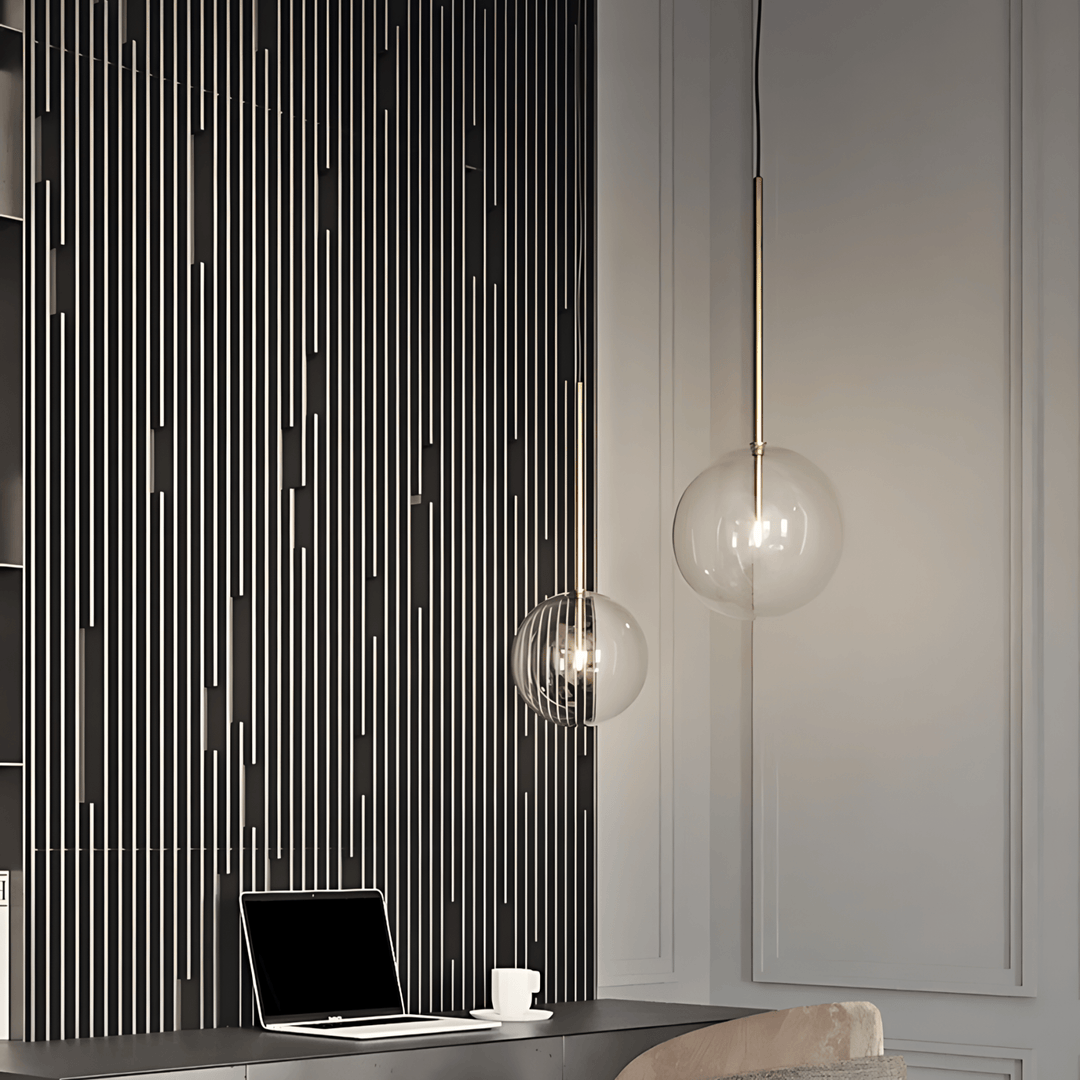 Modern glass pendant light with a sleek metal stem, illuminating a desk area.
