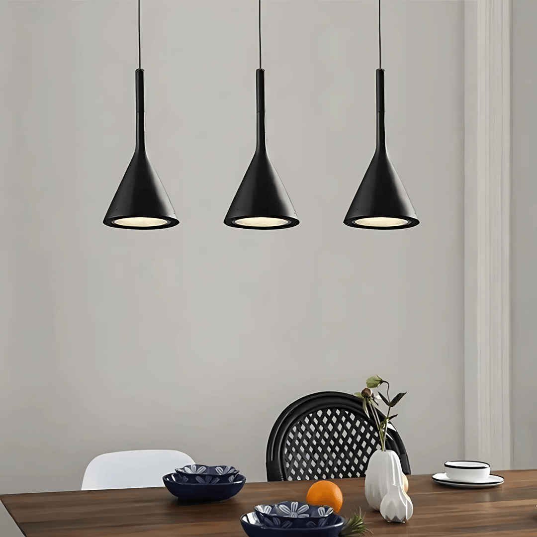 Three black cone pendant lights hanging over a dining table.