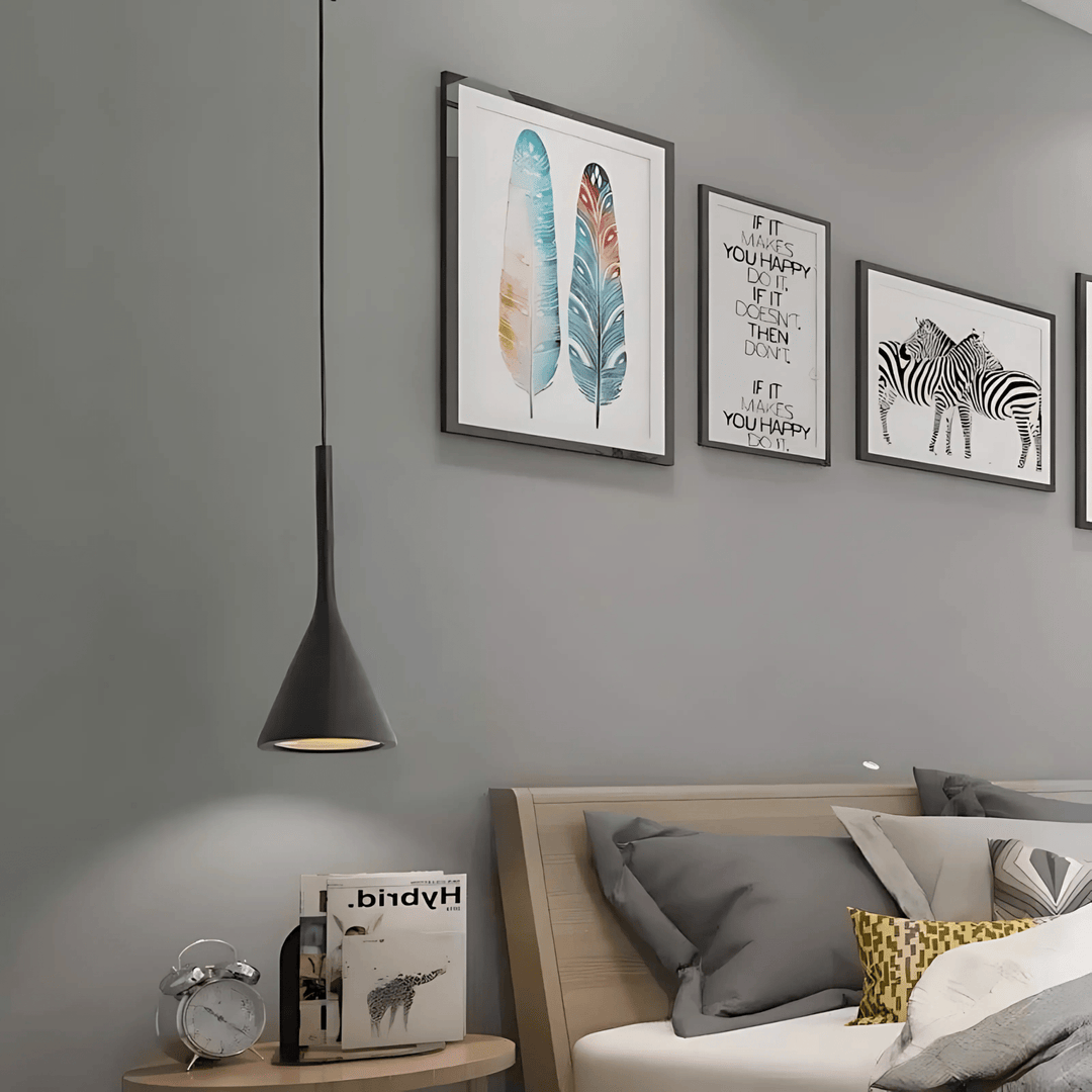 Black cone pendant light hanging over a nightstand with a clock and books.