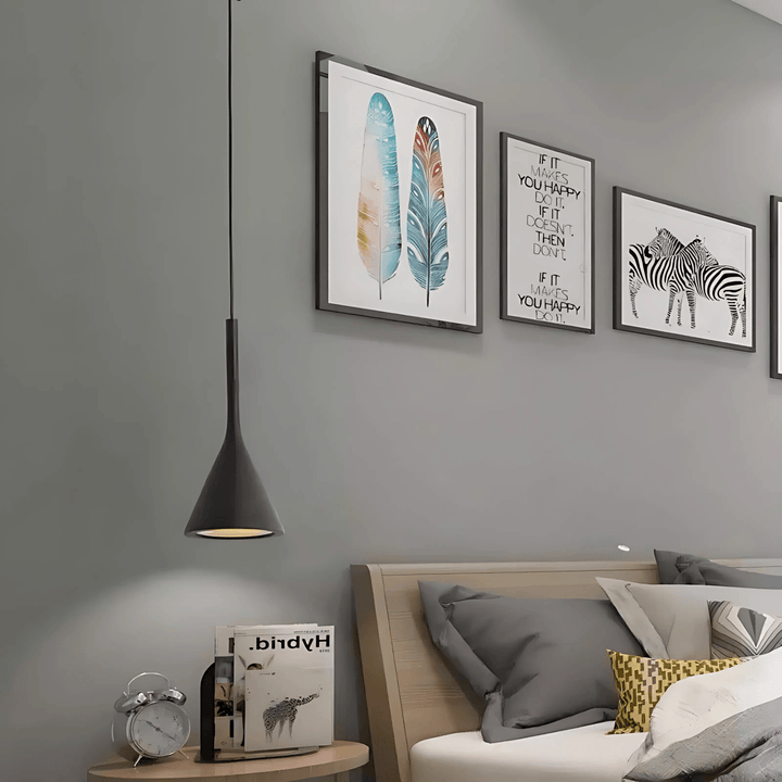 Black cone pendant light hanging over a nightstand with a clock and books.