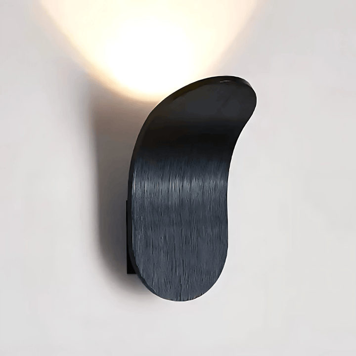 Black curved metal wall sconce with a textured finish, casting a warm light upwards.