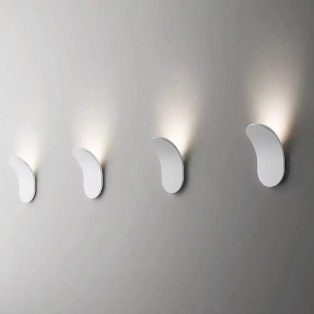 Four modern white metal wall sconces mounted on a gray wall, casting soft light upwards.
