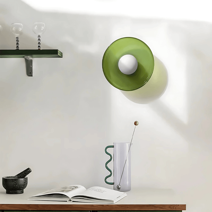 Green flush mount ceiling light with a white bulb inside, casting a shadow on the wall.