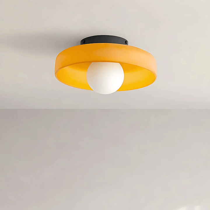 Flush mount ceiling light with a yellow shade and a white globe bulb.