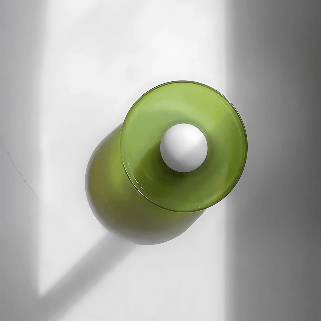 Green flush mount ceiling light with a white orb in the center, casting a shadow.