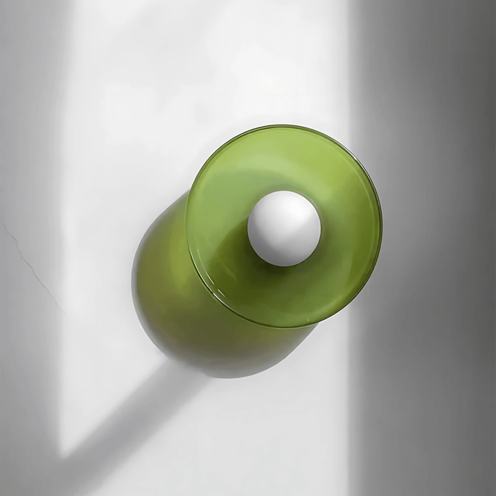 Green flush mount ceiling light with a white orb in the center, casting a shadow.