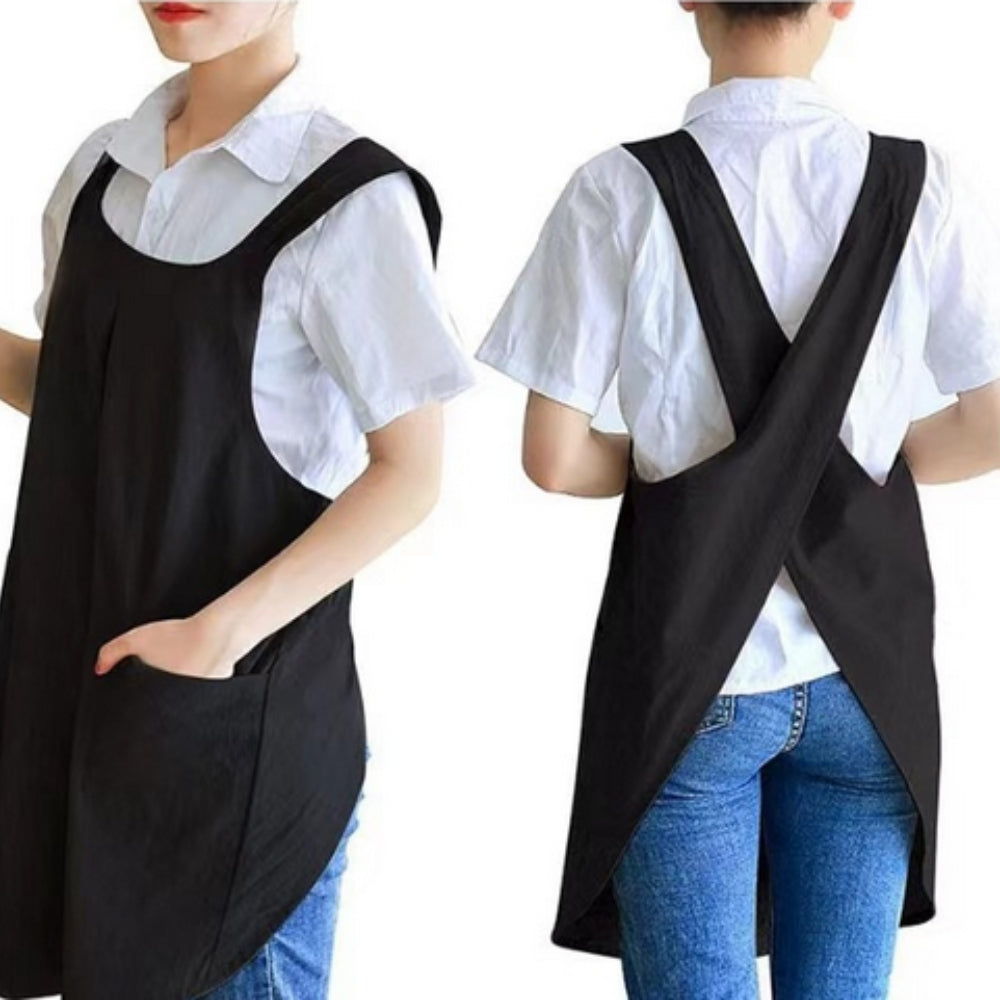 Black cross-back apron with wide straps and two front pockets, worn over a white shirt.