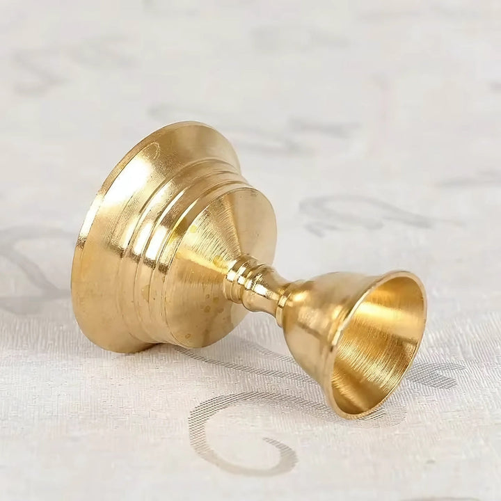 Vintage copper cup candle holder with a pedestal base, lying on its side.