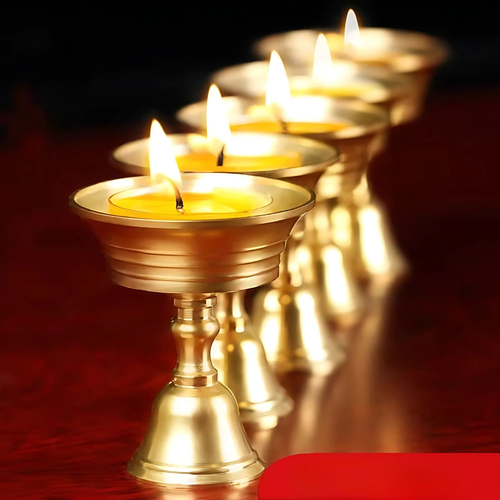 Row of vintage copper cup candle holders with lit yellow candles.