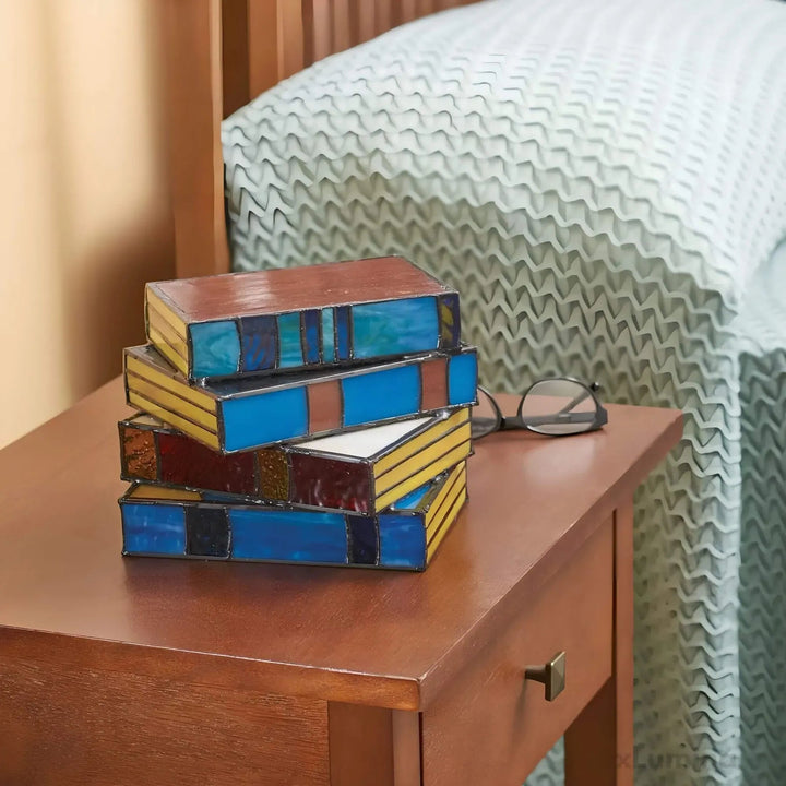 Stained glass table lamp designed to look like a stack of colorful books, casting a warm ambient glow.
