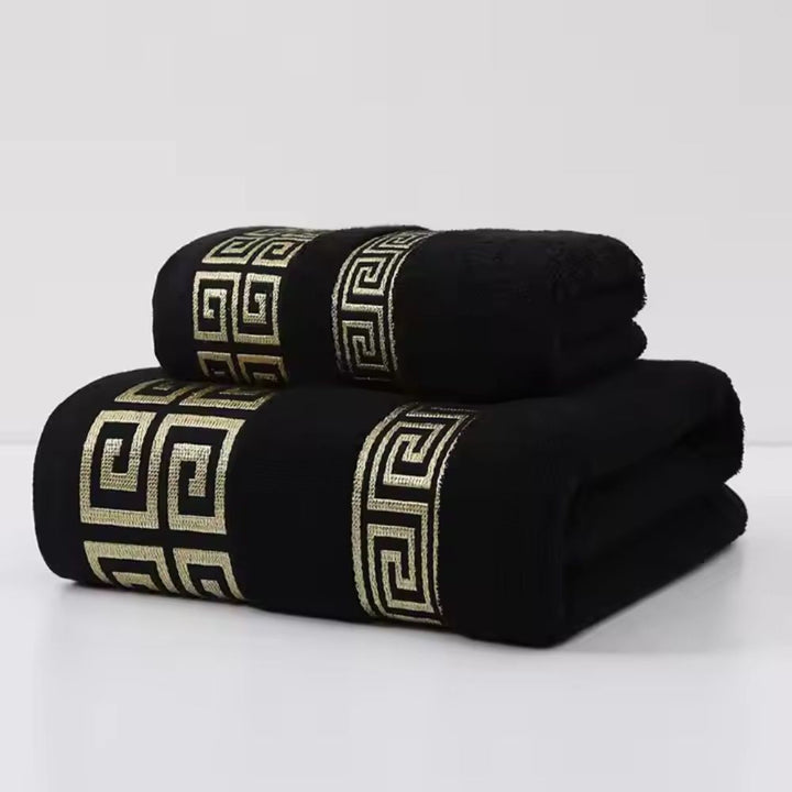 Two black cotton towels with a gold Greek key pattern band.