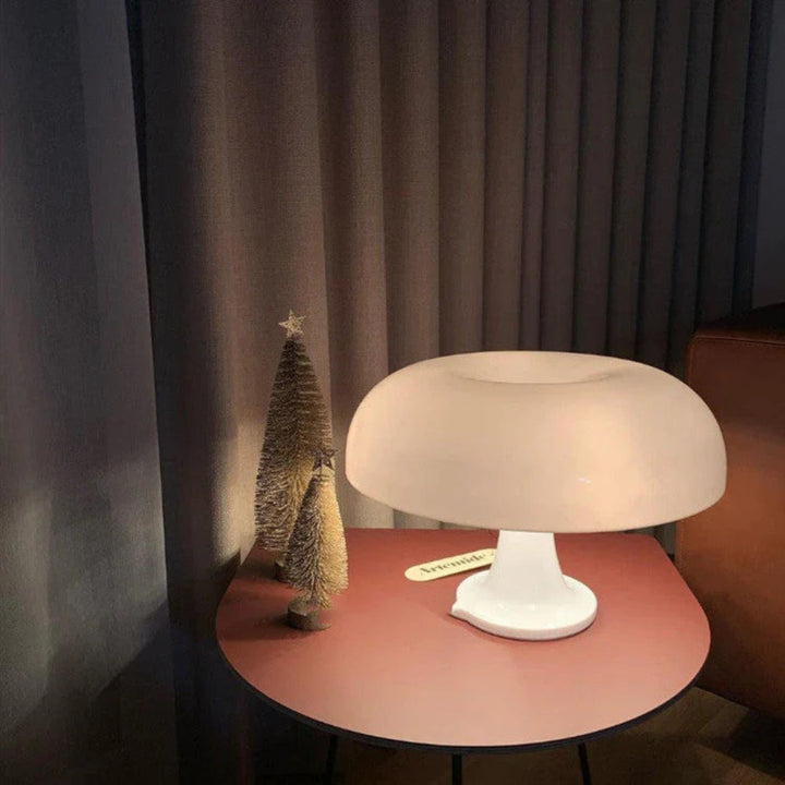 White mushroom-shaped LED table lamp on a red side table with two small decorative trees.