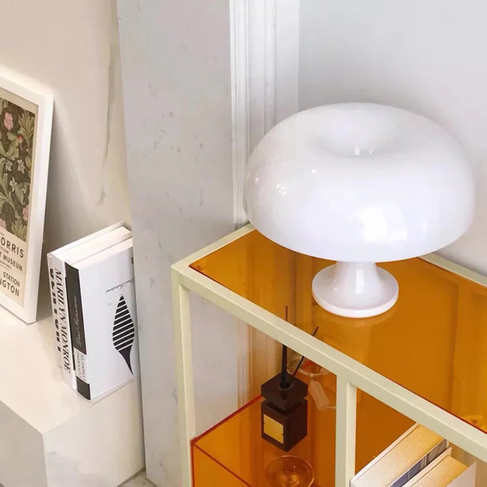 White mushroom-shaped LED table lamp on an orange shelf next to books and a diffuser.