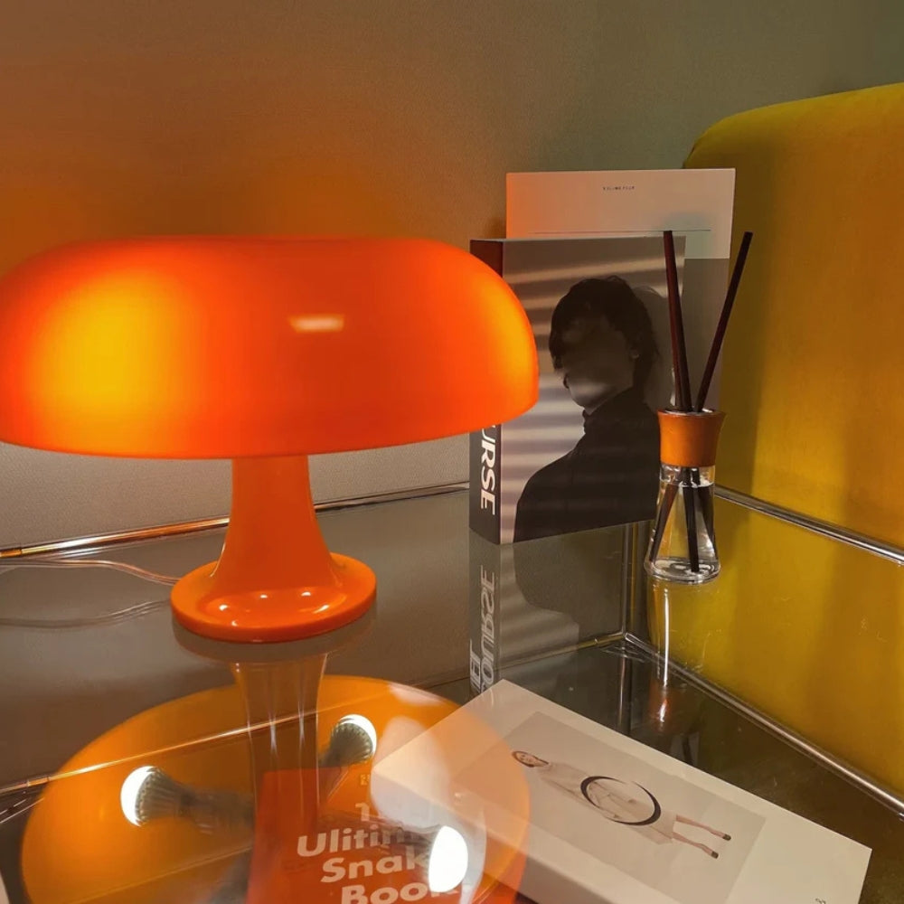 Orange mushroom-shaped LED table lamp with a soft glow, placed on a glass table.