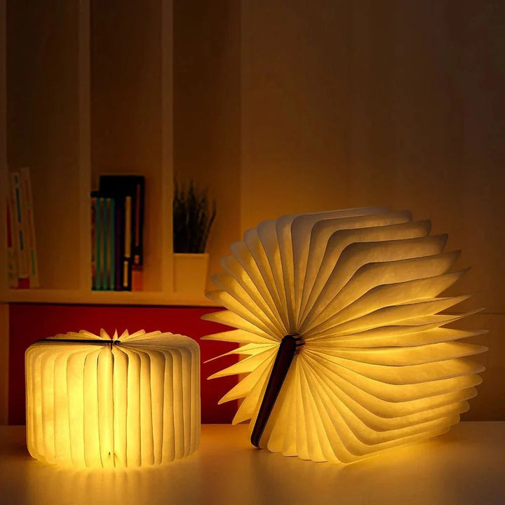 Two LumiFold table lamps, one closed and one open like a fan, casting a warm glow.