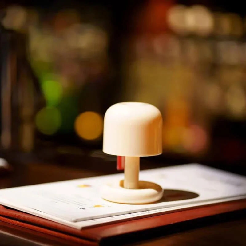 Cream colored USB rechargeable table lamp with a rounded shade and a short stem on a menu.