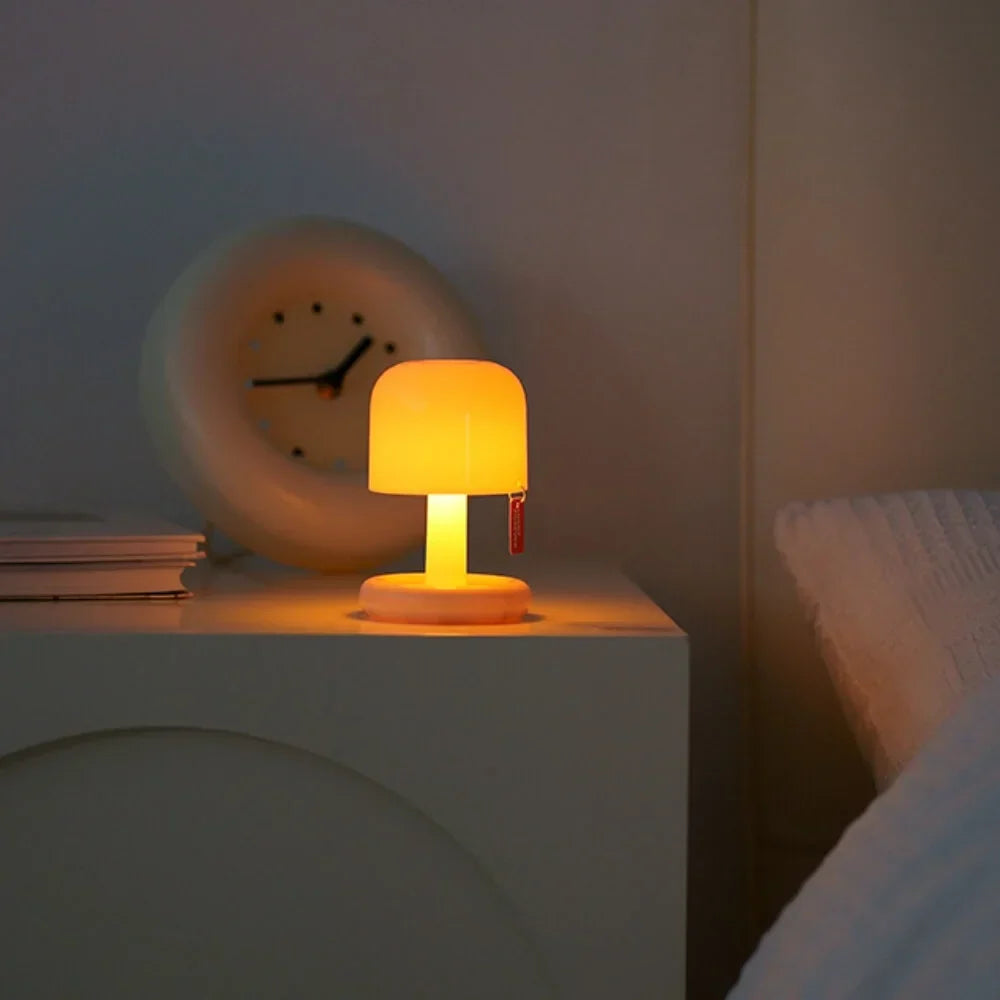 Compact USB rechargeable table lamp with a rounded shade and a short stem, emitting warm white light.