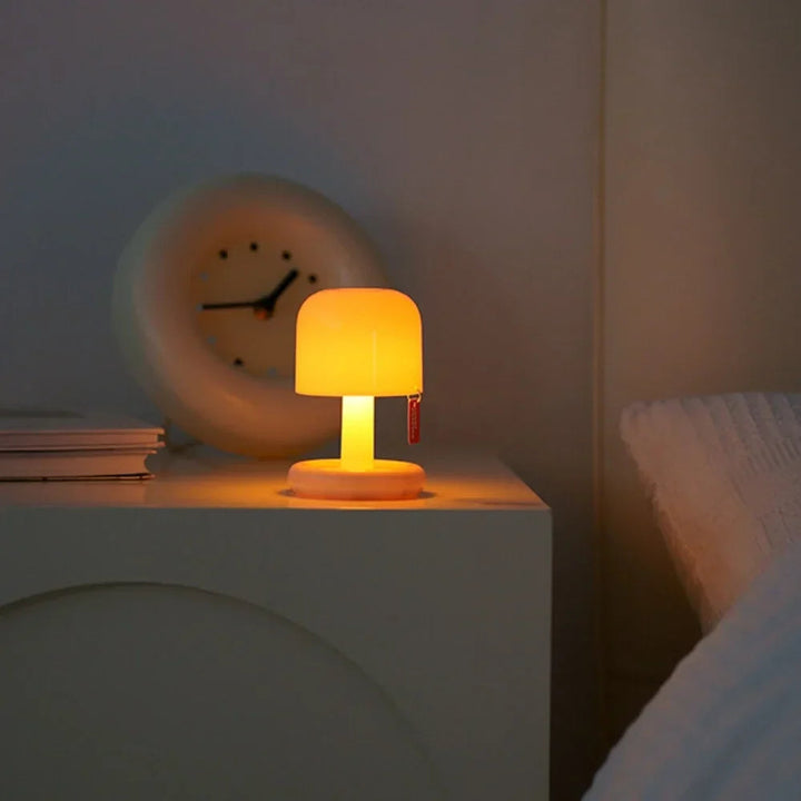 Compact USB rechargeable table lamp with a rounded shade and a short stem, emitting warm white light.