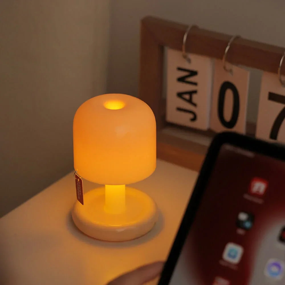 Compact USB rechargeable table lamp with a warm orange glow on a bedside table.
