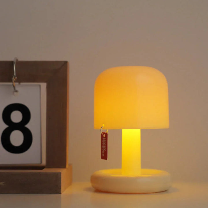 A compact, modern USB rechargeable table lamp with a rounded shade and a small red tag that says &