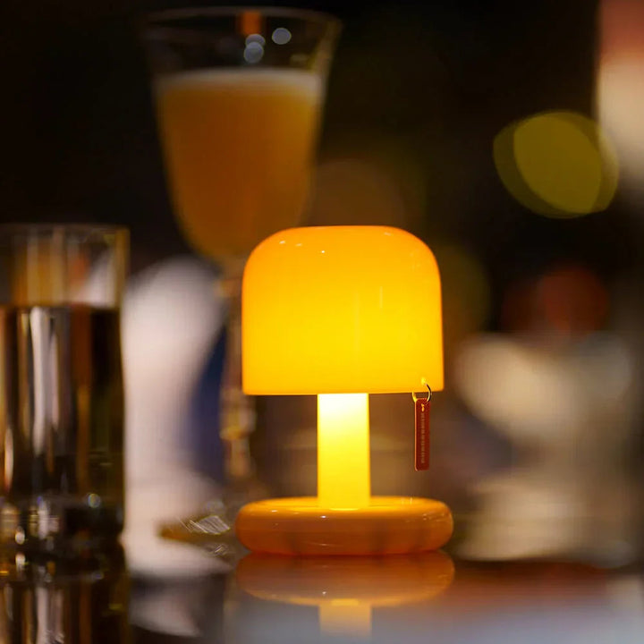 Orange USB rechargeable table lamp with a rounded shade and a small red tag.