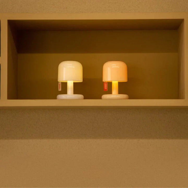 Two compact, modern USB rechargeable table lamps with rounded shades on a shelf.