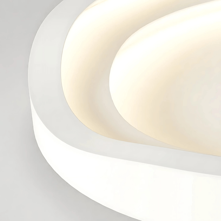 Metal flush mount ceiling light with curved, layered design in white and cream.