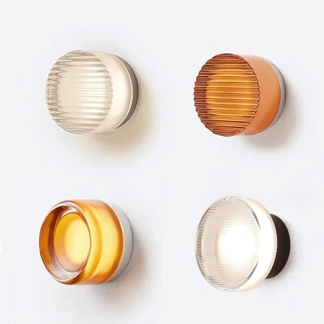 Four modern wall sconces with textured glass in clear and amber hues, mounted on metal bases.