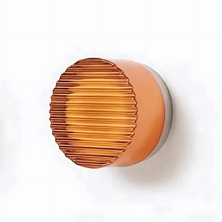 A round, ribbed glass sconce with an amber glow, mounted on a grey base against a white background.