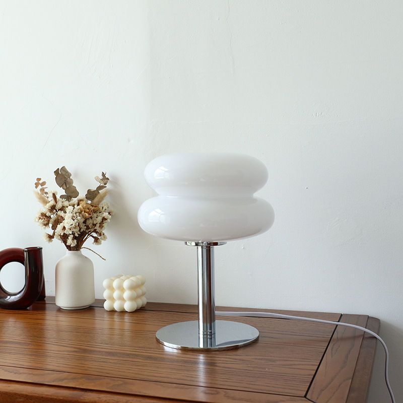 Retro glass table lamp with a white double-bubble shade and chrome base on a wooden table.