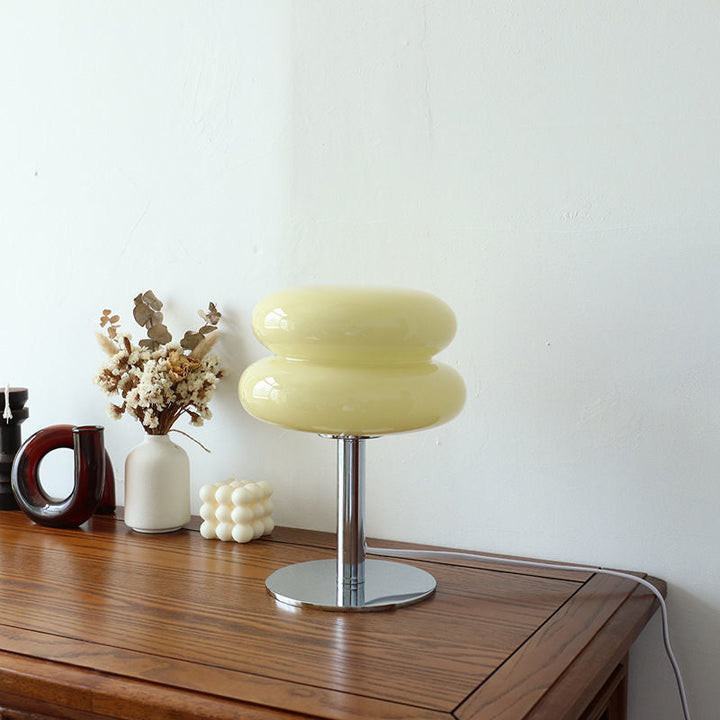 Retro glass table lamp with a yellow shade and chrome base on a wooden table.