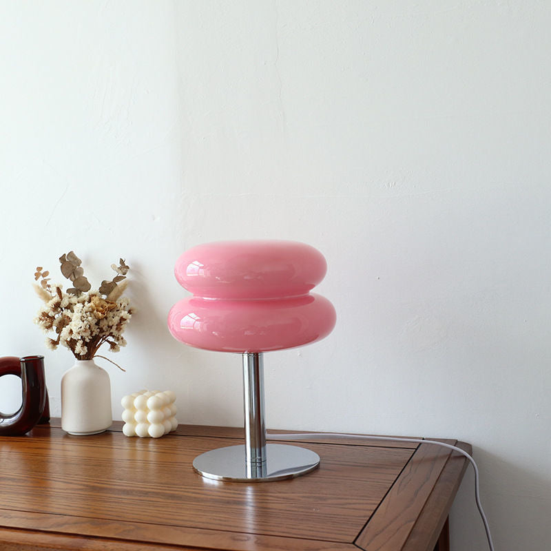 Pink retro glass table lamp with a chrome base on a wooden table.