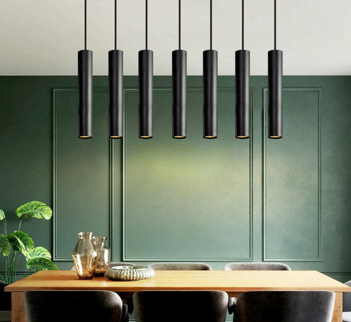 Black adjustable pendant light hanging above a wooden dining table with green walls.