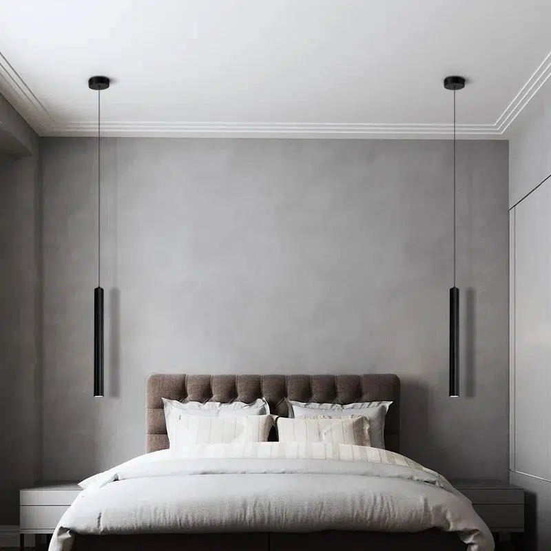 Two black adjustable pendant lights hanging over a bed in a modern bedroom.