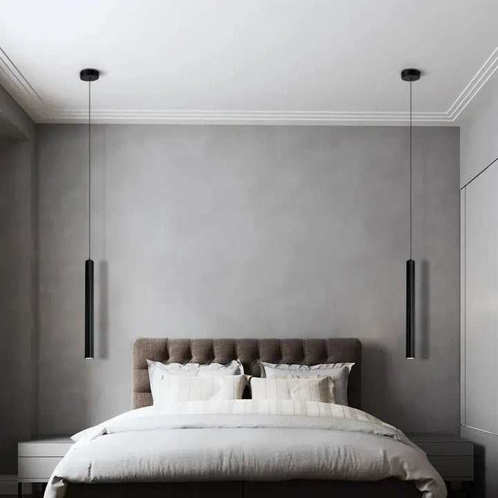 Two black adjustable pendant lights hanging over a bed in a modern bedroom.